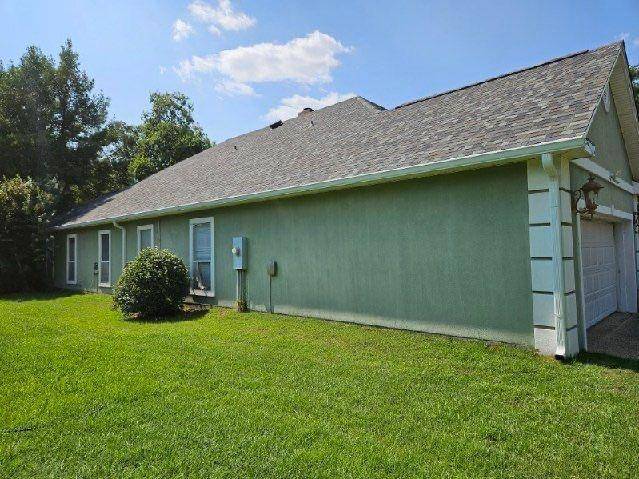 Green stucco house seen from the side with a new gray shingle roof