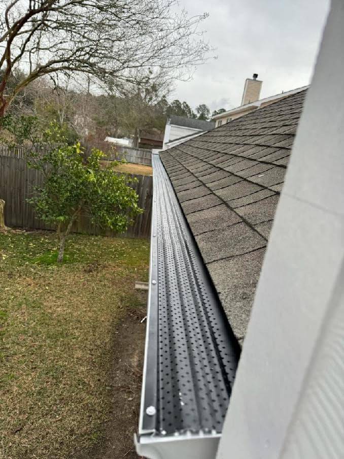 White gutter with a perforated gutter guard under new shingles