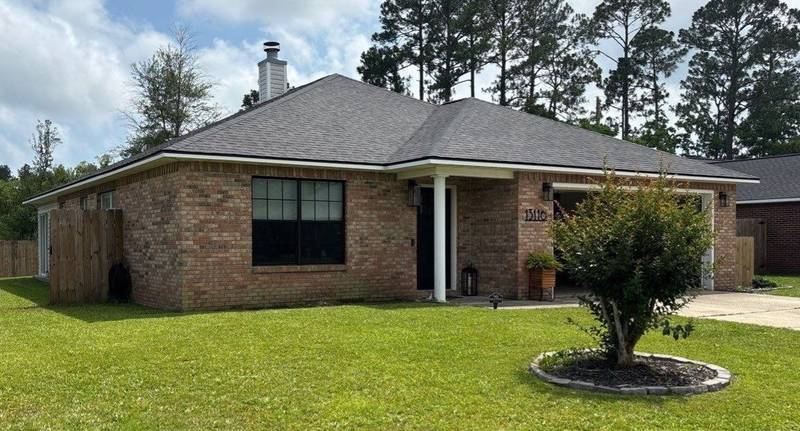 Brick house with a new dark shingle roof and a round flower bed in front