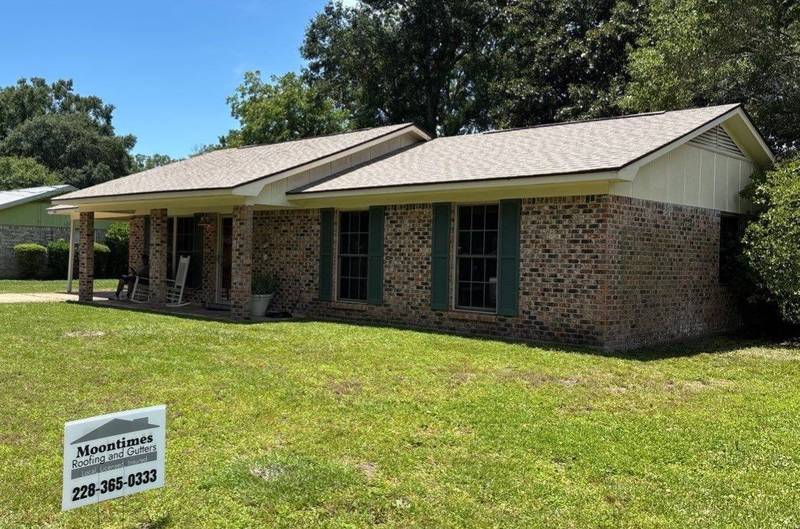 Brick ranch house with a new light-brown shingle roof and a company yard sign on the lawn